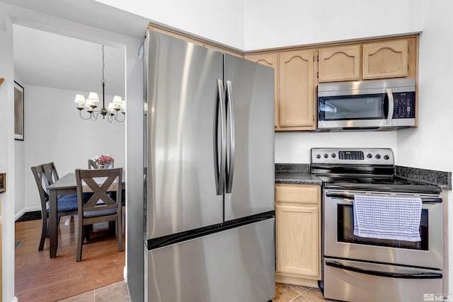 kitchen with light tile patterned floors, a notable chandelier, light brown cabinets, and stainless steel appliances