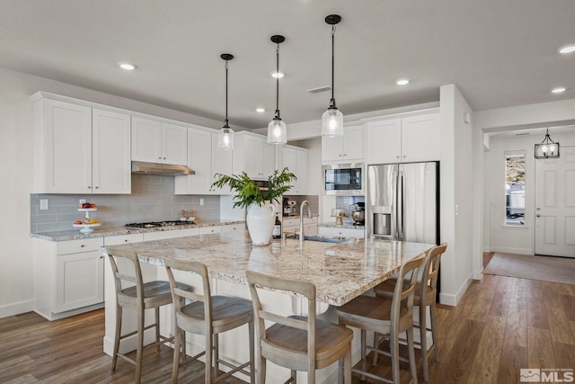 kitchen with white cabinets, appliances with stainless steel finishes, sink, and a center island with sink