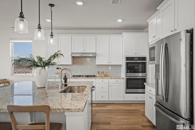 kitchen with decorative light fixtures, a breakfast bar, white cabinetry, and appliances with stainless steel finishes