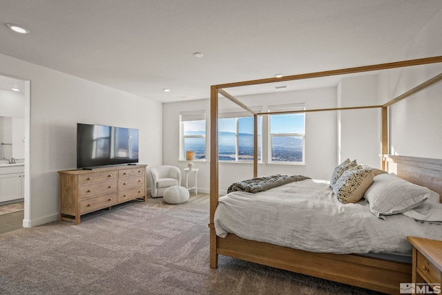 bedroom featuring ensuite bathroom and carpet flooring