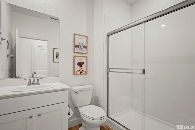 bathroom with toilet, an enclosed shower, and vanity