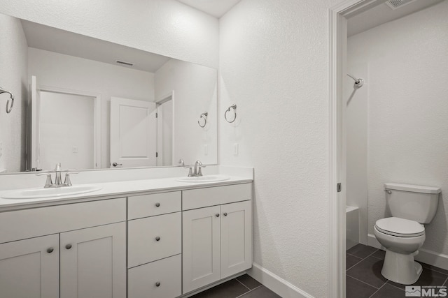 bathroom with toilet, vanity, and tile patterned flooring