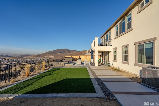 view of yard featuring central AC unit, a balcony, a mountain view, and a patio