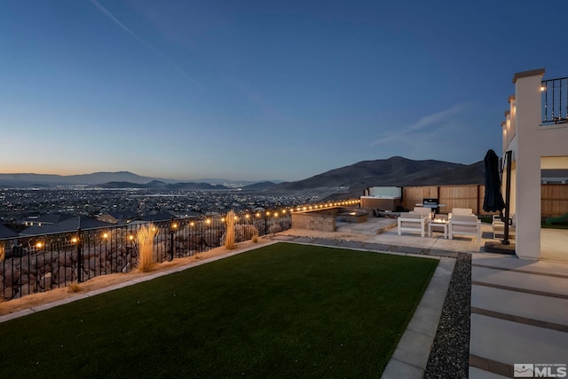 yard at dusk featuring an outdoor living space, a patio area, and a mountain view