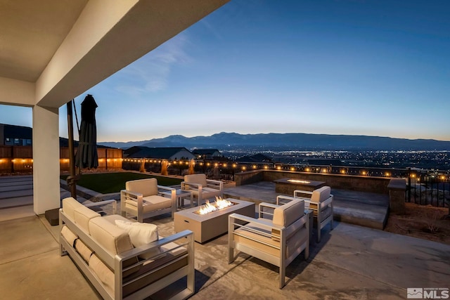 patio terrace at dusk with an outdoor living space with a fire pit and a mountain view