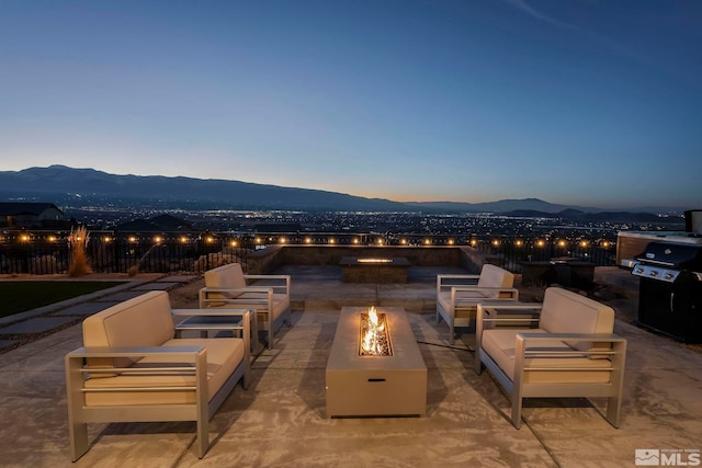 patio terrace at dusk featuring a mountain view and a fire pit