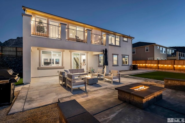 rear view of house with an outdoor living space with a fire pit, a balcony, and a patio