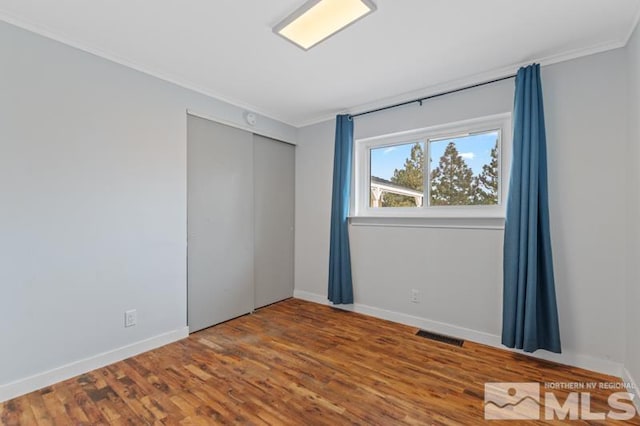 empty room with wood-type flooring and ornamental molding