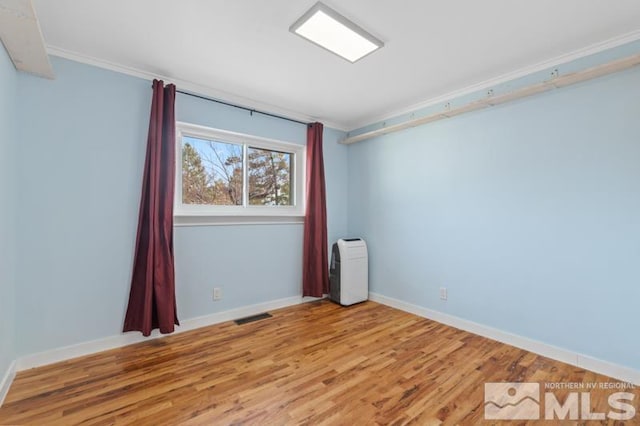 spare room featuring ornamental molding and hardwood / wood-style flooring