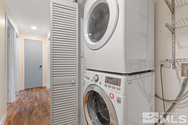 clothes washing area with stacked washer / dryer, dark hardwood / wood-style flooring, and crown molding