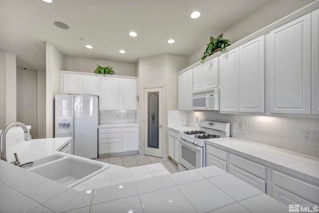 kitchen featuring tile counters, white cabinets, and white appliances