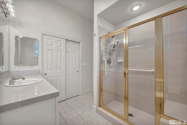 bathroom with an enclosed shower, vanity, and tile patterned flooring