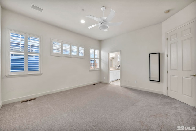 unfurnished bedroom featuring ceiling fan, ensuite bath, and light carpet