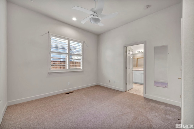 unfurnished bedroom featuring ensuite bath, light colored carpet, and ceiling fan