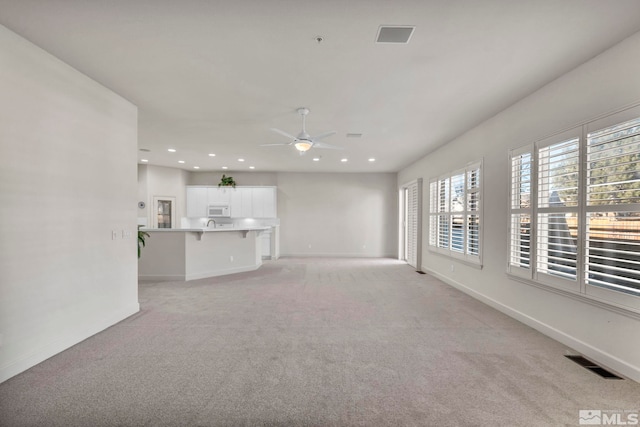 unfurnished living room with ceiling fan and light colored carpet