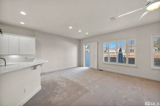 unfurnished living room with ceiling fan and light colored carpet