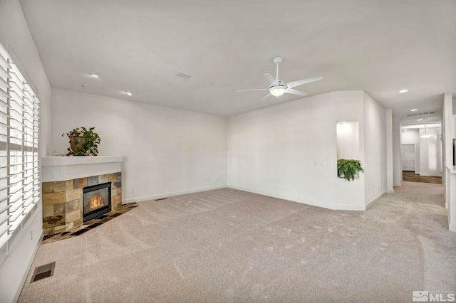 unfurnished living room featuring light carpet, ceiling fan, and a fireplace