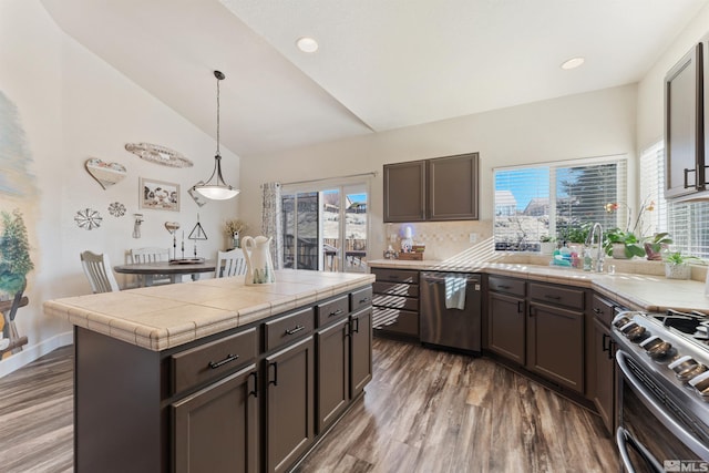 kitchen featuring appliances with stainless steel finishes, pendant lighting, a kitchen island, and dark brown cabinetry