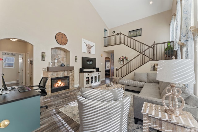 living room with dark hardwood / wood-style floors, a tiled fireplace, and high vaulted ceiling