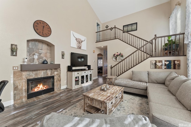 living room with high vaulted ceiling, wood-type flooring, a wealth of natural light, and a stone fireplace