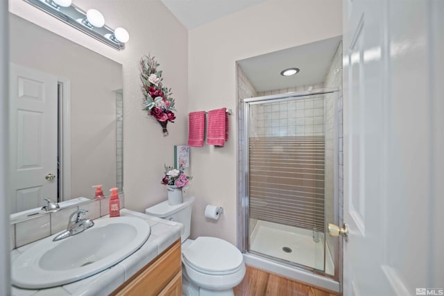 bathroom with hardwood / wood-style flooring, toilet, walk in shower, and vanity