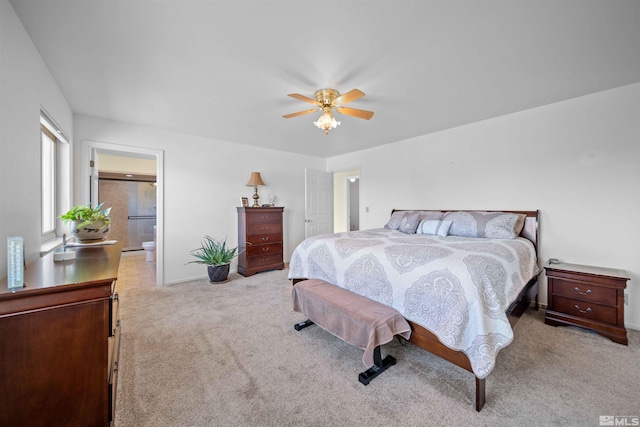 bedroom featuring ceiling fan, light colored carpet, and connected bathroom