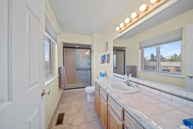 bathroom featuring toilet, tile patterned flooring, a shower with shower door, and vanity