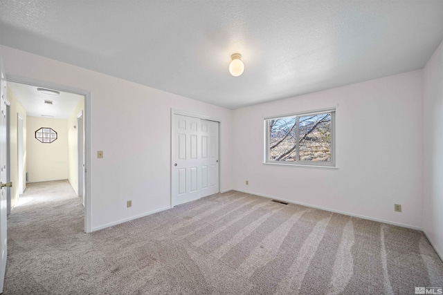 unfurnished bedroom with light colored carpet and a closet