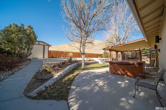 view of patio / terrace with a storage shed, a hot tub, and a mountain view