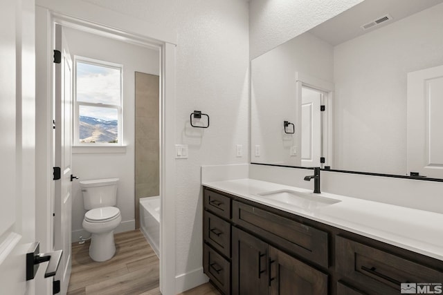 full bathroom with hardwood / wood-style floors, toilet, vanity, and tiled shower / bath combo