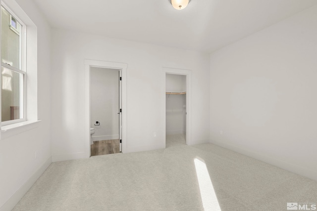 unfurnished bedroom featuring a spacious closet, multiple windows, a closet, and carpet