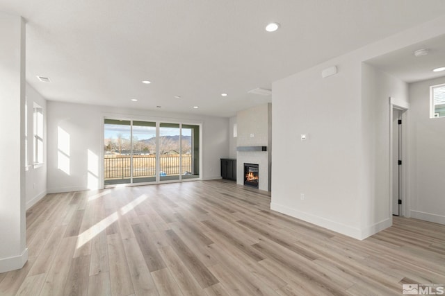 unfurnished living room with a fireplace and light hardwood / wood-style floors