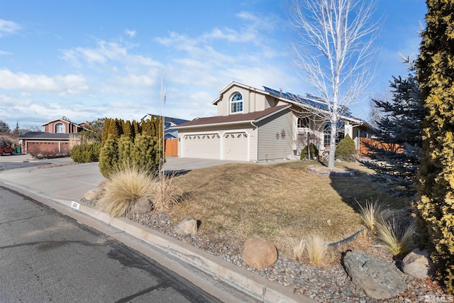 view of property featuring a front yard, solar panels, and a garage