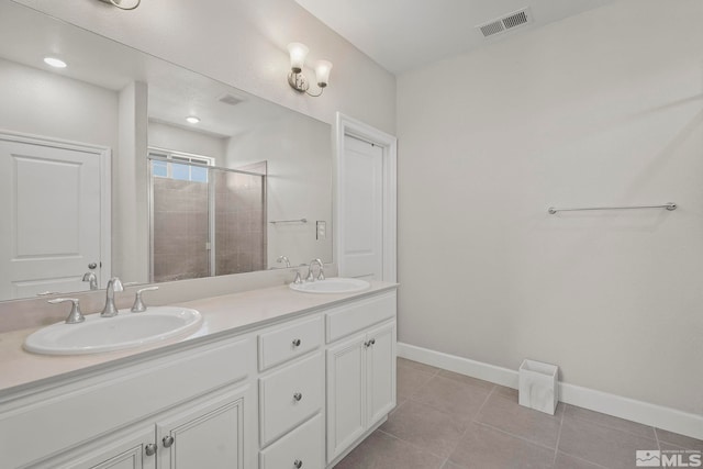 bathroom with a shower with shower door, vanity, and tile patterned flooring