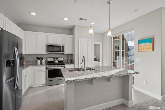 kitchen with white cabinetry, appliances with stainless steel finishes, a kitchen island with sink, pendant lighting, and sink