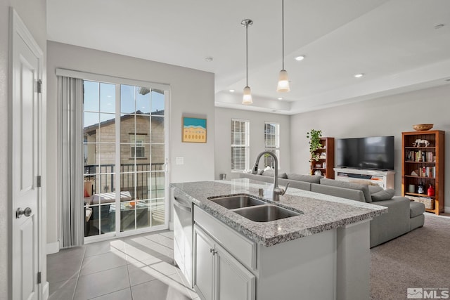 kitchen featuring white cabinetry, a kitchen island with sink, light stone countertops, pendant lighting, and sink