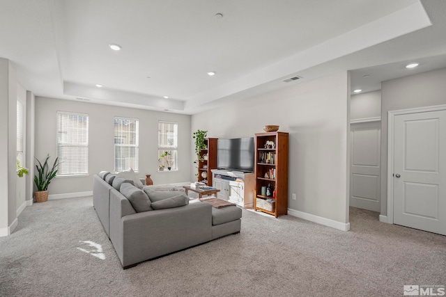 living room featuring light carpet and a raised ceiling