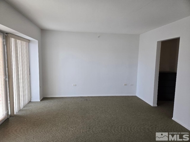 spare room with dark colored carpet