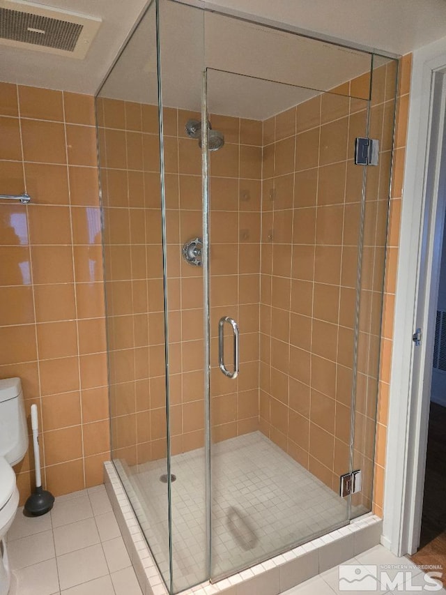 bathroom featuring toilet, tile patterned flooring, and a shower with door