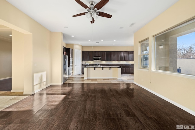 unfurnished living room featuring light wood-type flooring, ceiling fan, and sink