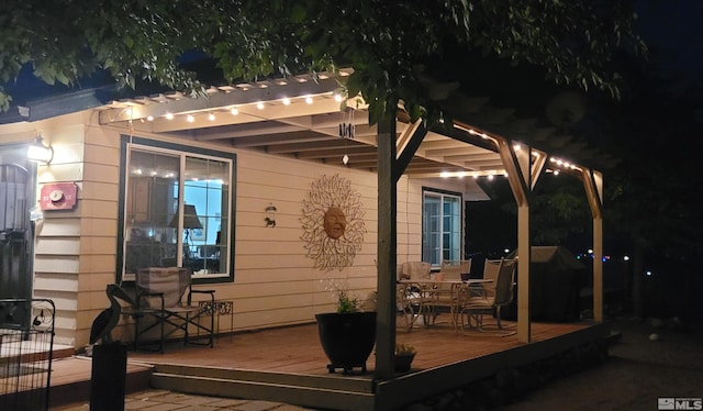 deck at night featuring a pergola