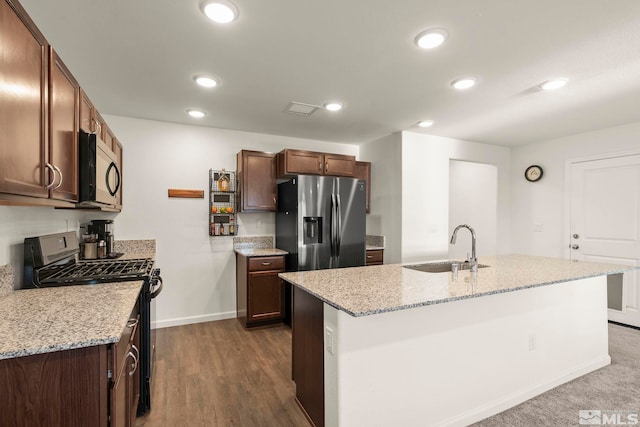 kitchen featuring an island with sink, light stone countertops, appliances with stainless steel finishes, and sink