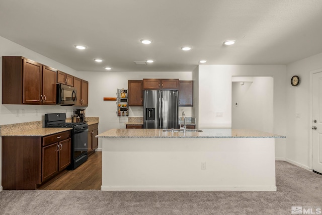 kitchen with black appliances, a kitchen island with sink, sink, and dark colored carpet