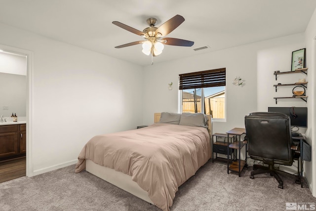 bedroom with ceiling fan, light colored carpet, ensuite bathroom, and sink