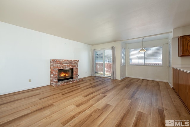 unfurnished living room with a brick fireplace and light hardwood / wood-style floors