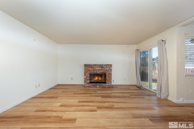 unfurnished living room with a brick fireplace and light hardwood / wood-style floors