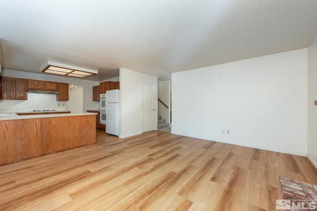 kitchen featuring white appliances, light hardwood / wood-style flooring, and kitchen peninsula