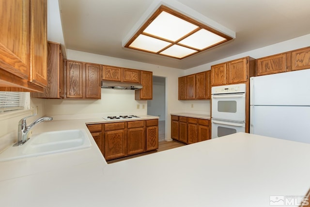 kitchen with kitchen peninsula, sink, and white appliances