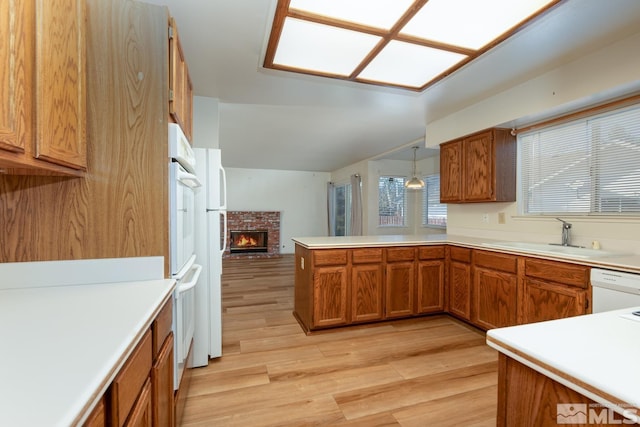 kitchen with light hardwood / wood-style floors, white appliances, a fireplace, pendant lighting, and sink