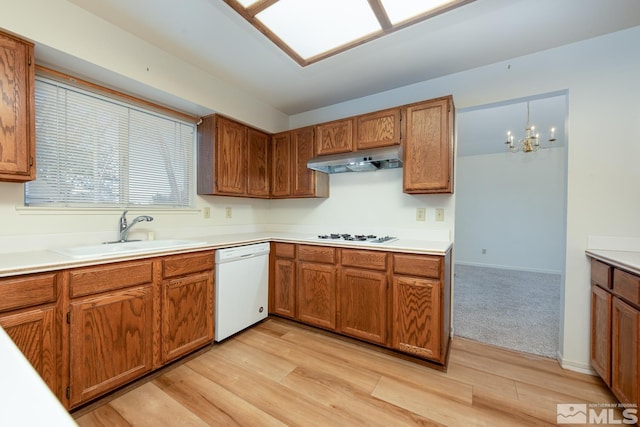 kitchen featuring an inviting chandelier, light hardwood / wood-style floors, white appliances, hanging light fixtures, and sink